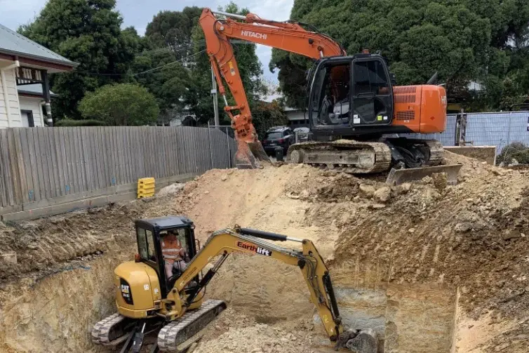 Yellow excavator digging at a residential construction site in Victoria BC